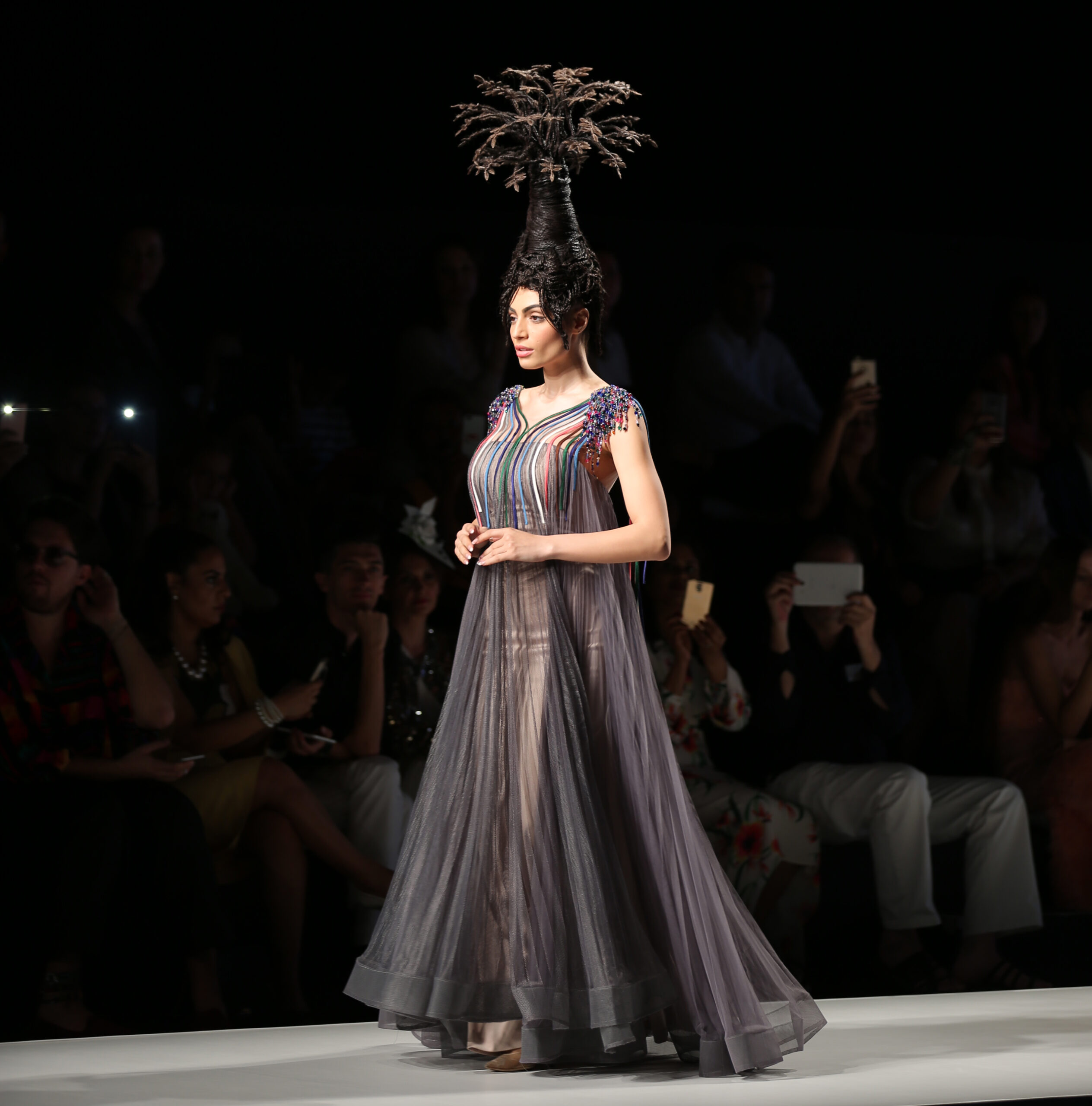 Model walking the runway at Arab Fashion Week, showcasing the "Tree of Life" hairstyle by hairstylist Fadi Nasr, crafted using hair and a platform, paired with a flowing lavender gown
